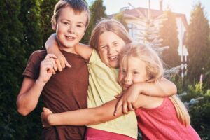 Three children smiling and hugging